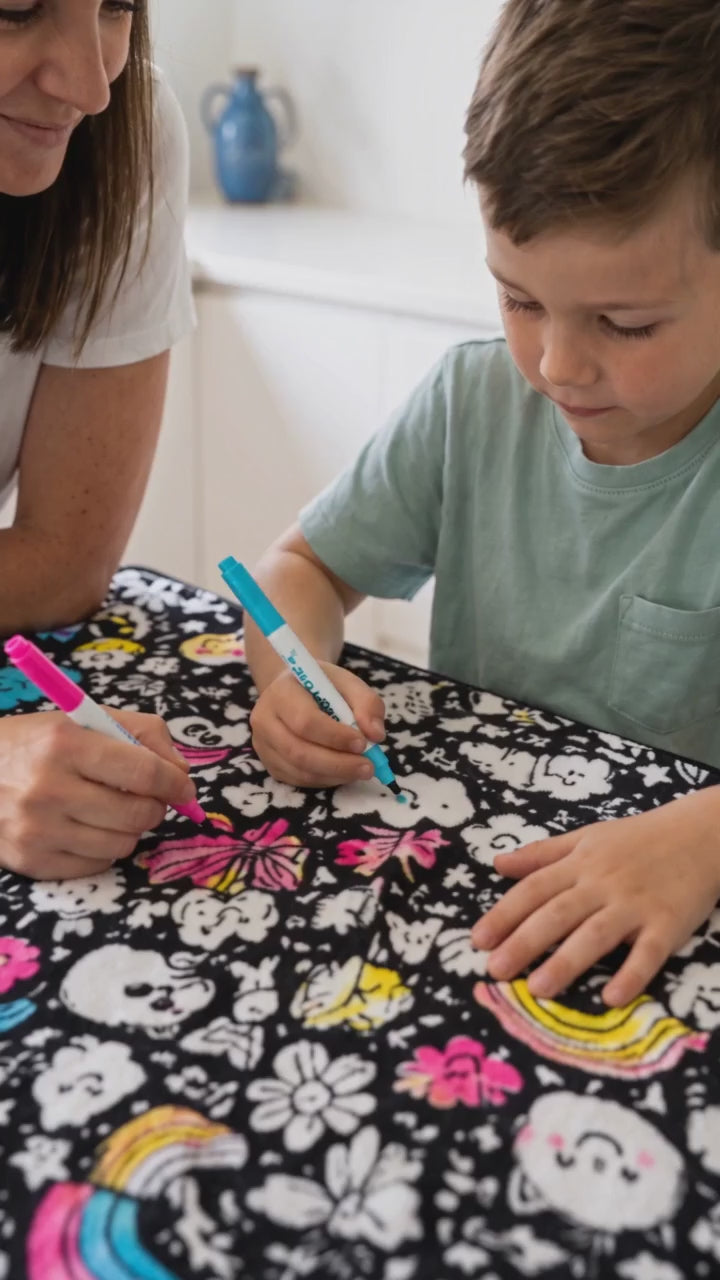 Illustrative AI scene: a mother and son coloring a Scriblo blanket at a table.
